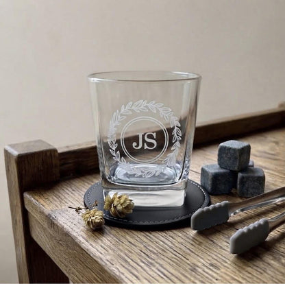 Engraved whiskey glass with stones and tongs on coaster